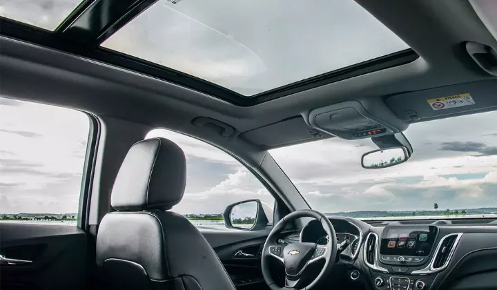 Fotografia feita do interior do veículo mostrando o teto solar panorâmico e um pouco do painel do SUV Equinox