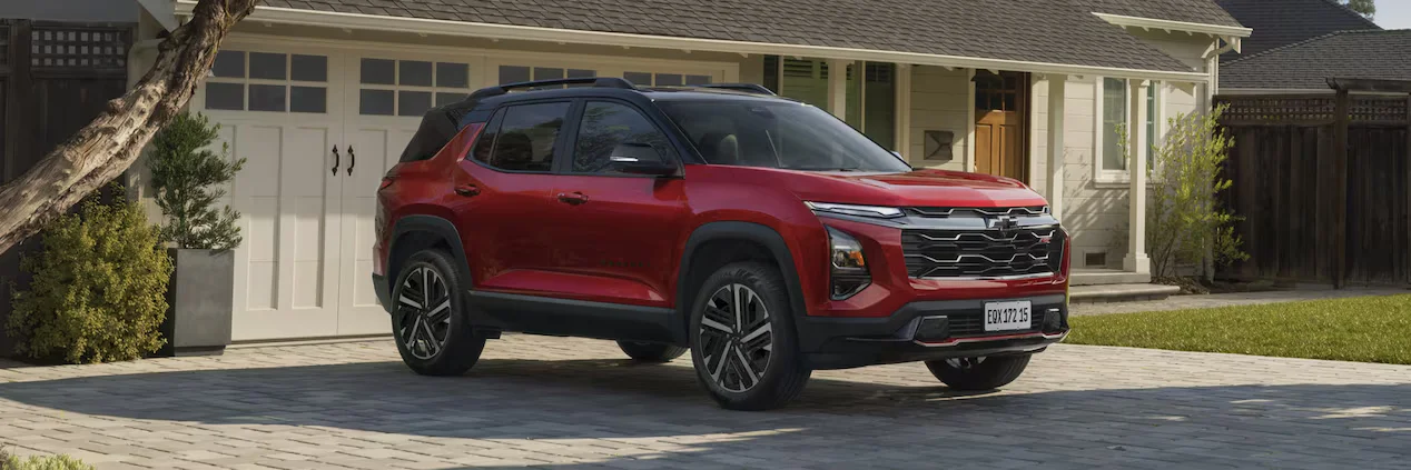 Chevrolet Equinox 2025 RS na cor vermelha, estacionado em frente a uma garagem, destacando sua frente robusta e design moderno.